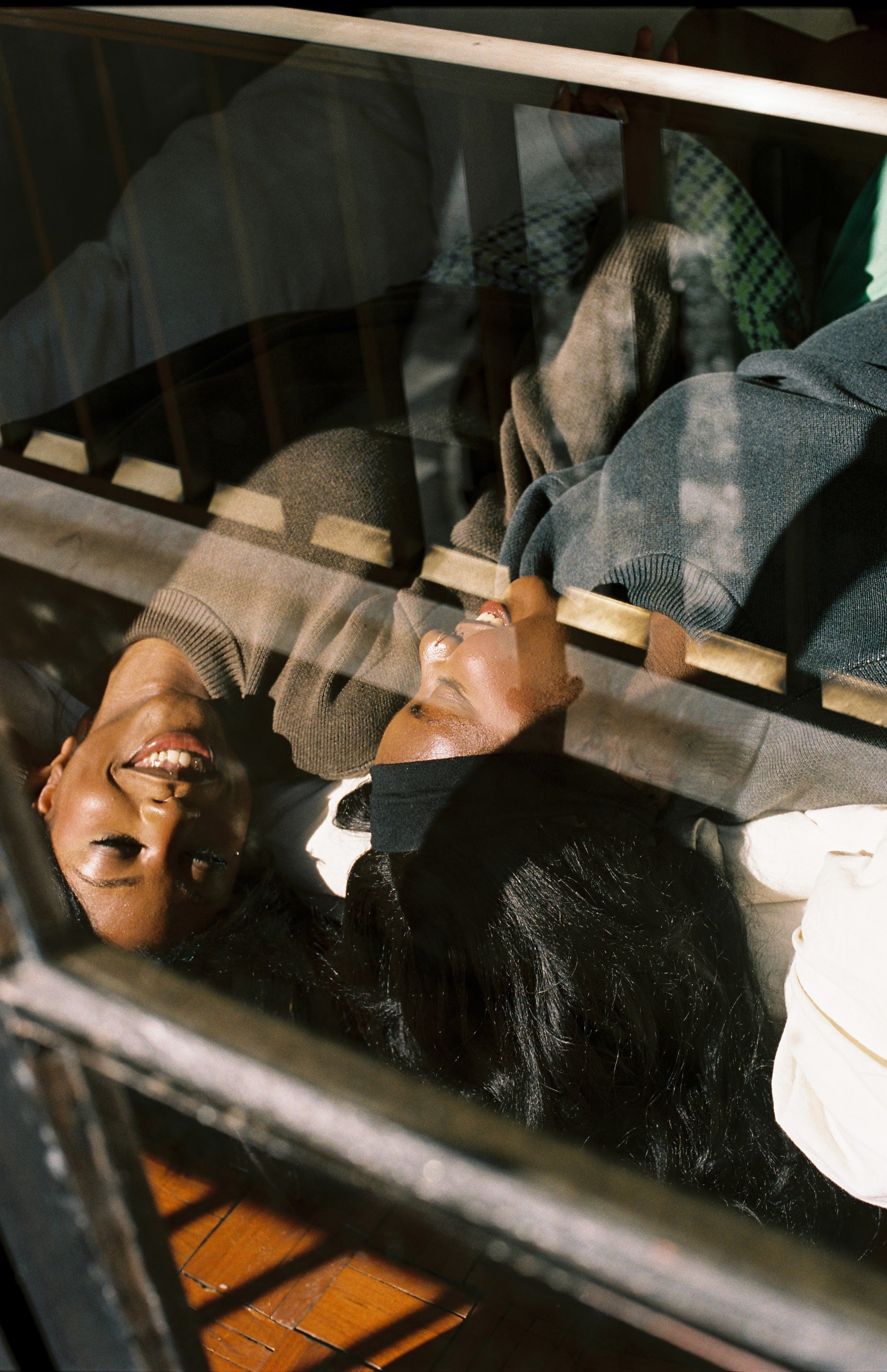 Two sisters lying together behind a railing in warm afternoon light, seen from above