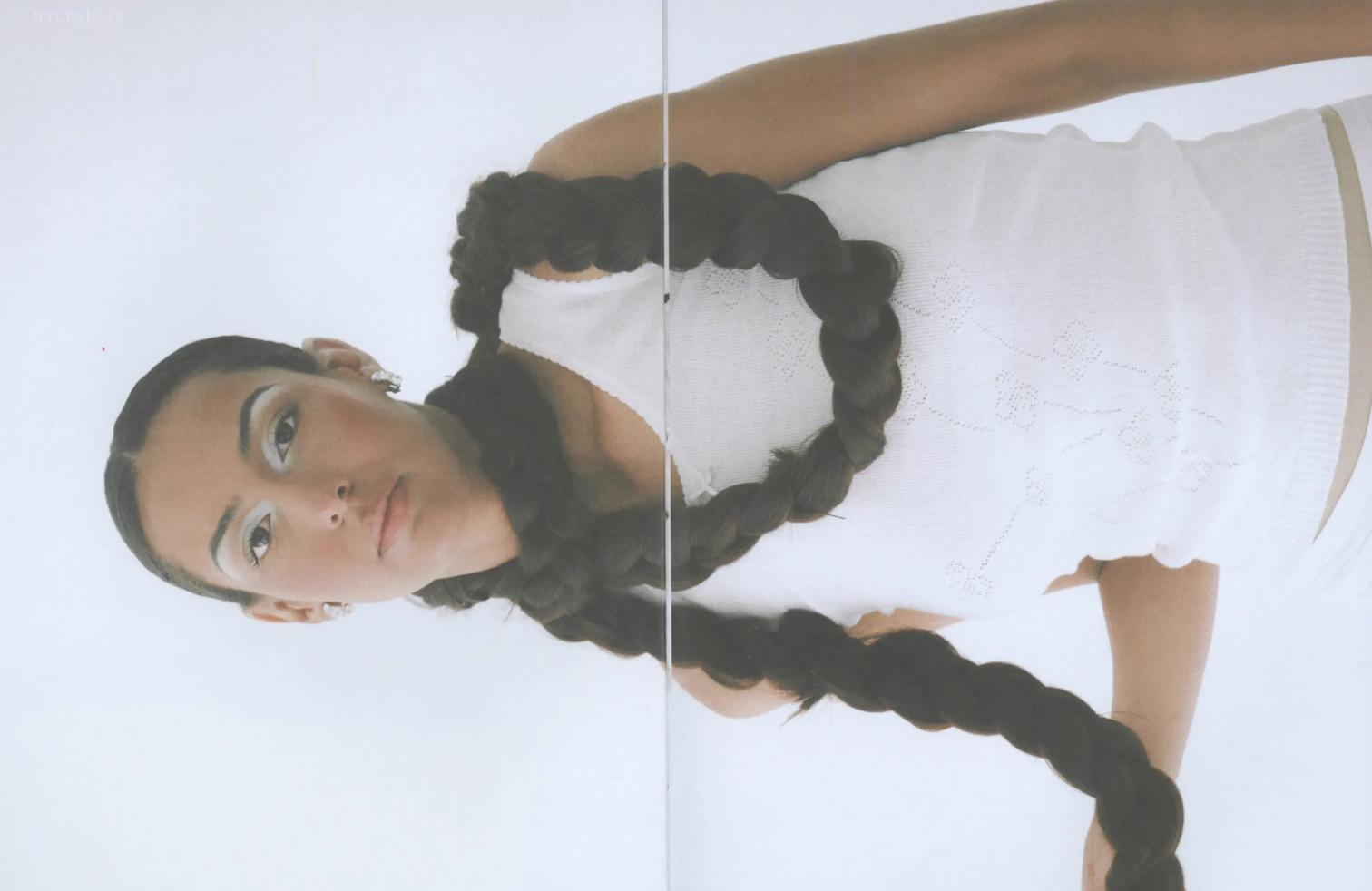 A figure lying with two long braids fanning out across white